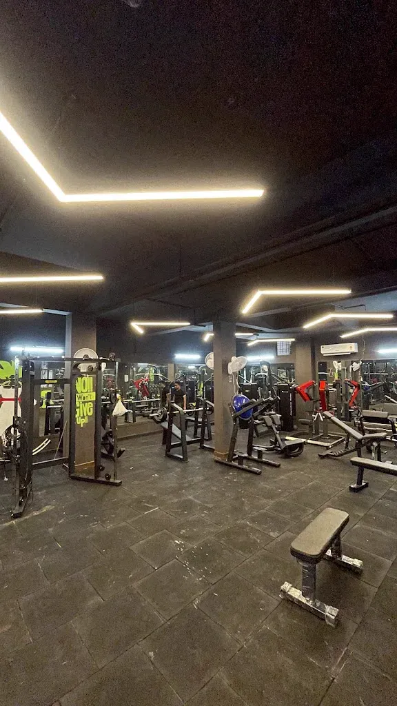 The main training floor at The Radium Gym, lined with plate-loaded machines, a cable station, free-weight benches and a squat area under strip lighting